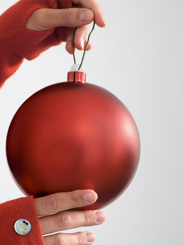 Gloved hands holding a red ornament.