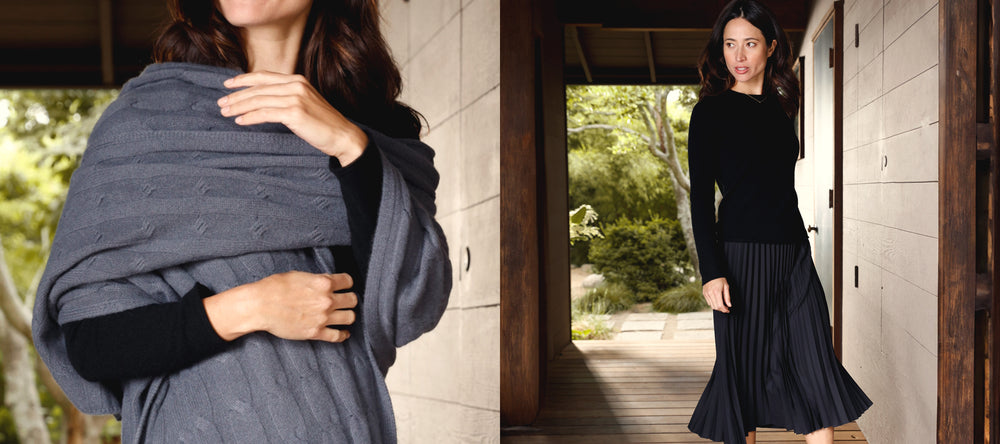 Two images of a woman wearing a cashmere black tee and pleated skirt styled with a grey cashmere wrap.