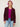 Woman wearing The Inverness Jacket, a purple cardigan by Margaret O'Leary, a pink shirt, and blue jeans on a white background