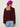 Woman wearing The Inverness Jacket, a purple cardigan by Margaret O'Leary, a pink shirt, and blue jeans on a white background