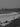 Black and white photo of a beach scene with people and boats.