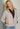 Woman wearing a beige cashmere Tahoe Zip Up sweater by Margaret O'Leary with a plain background.