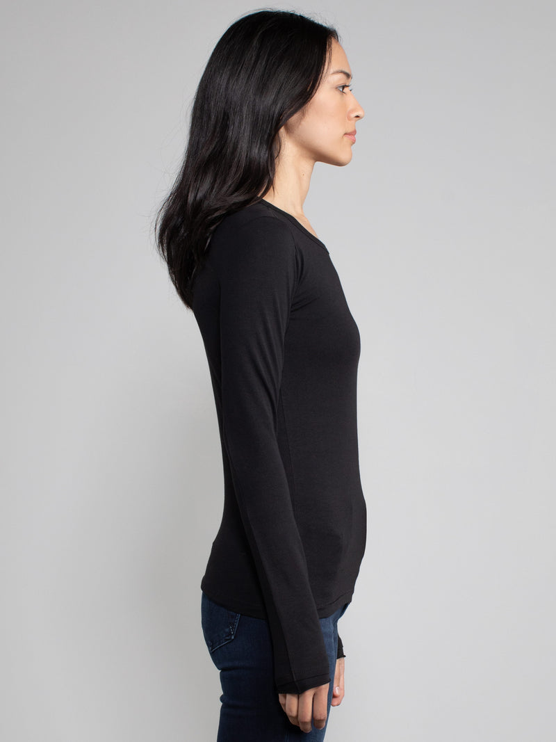 Side view of a woman wearing a black fitted long sleeve tee.