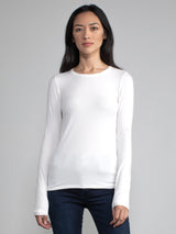 Portrait view of a woman wearing a white fitted long sleeve tee.
