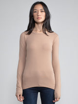 Portrait view of a woman wearing a light brown fitted long sleeve tee.