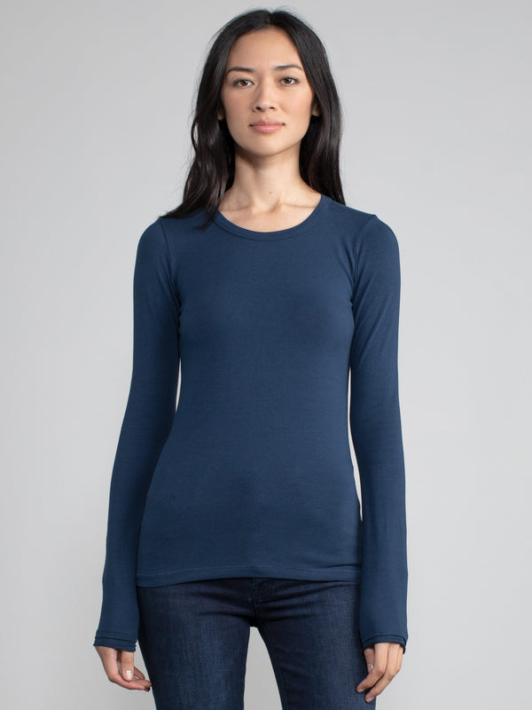 Portrait view of a woman wearing a navy fitted long sleeve tee.