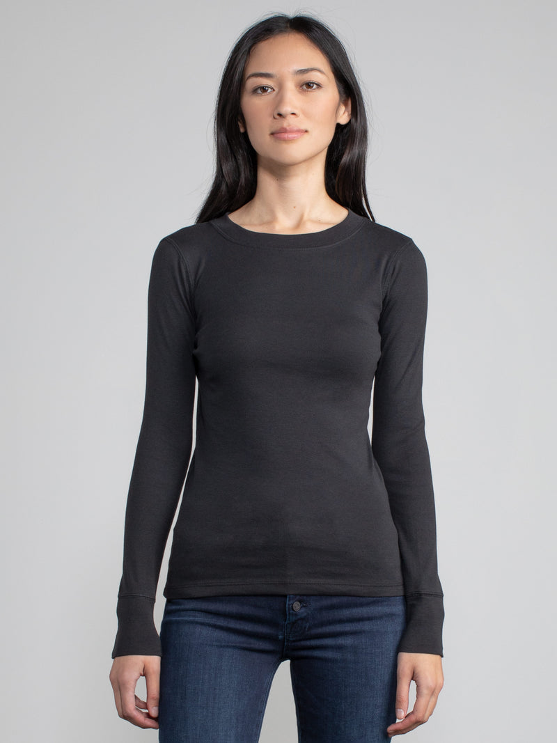 Portrait view of a woman wearing a black fitted long sleeve tee.
