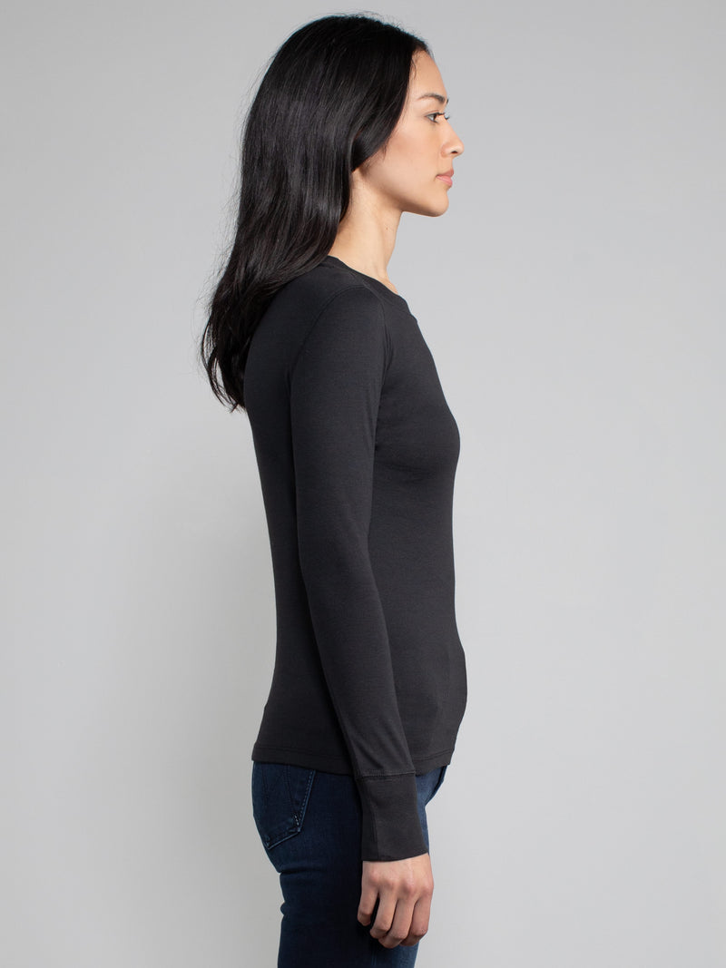 side view of a woman wearing a black fitted long sleeve tee.