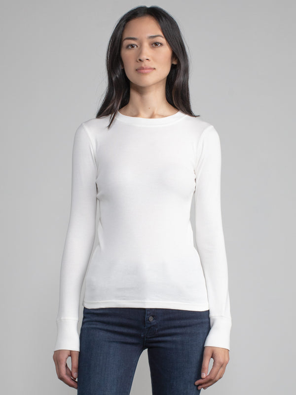 Portrait view of a woman wearing a white fitted long sleeve tee.