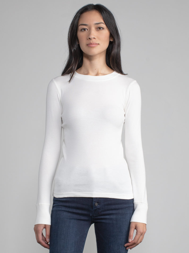 Portrait view of a woman wearing a white fitted long sleeve tee.
