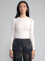Portrait view of a woman wearing a solid oat fitted long sleeve tee.