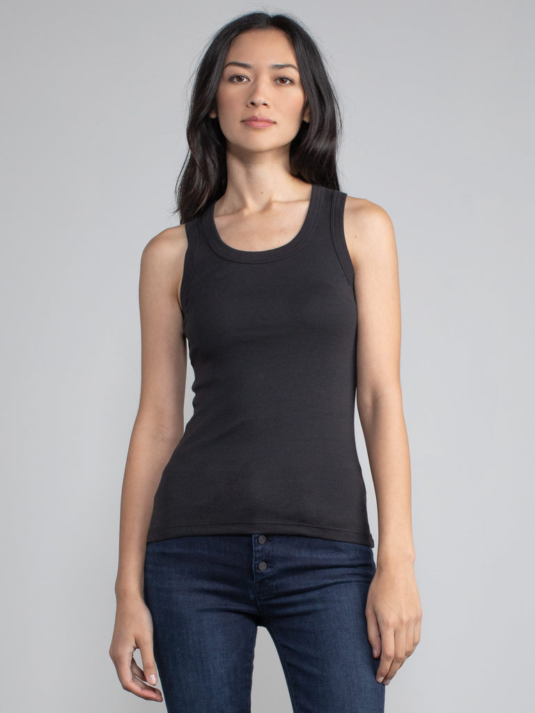 Portrait view of a woman wearing a fitted ribbed black tank.