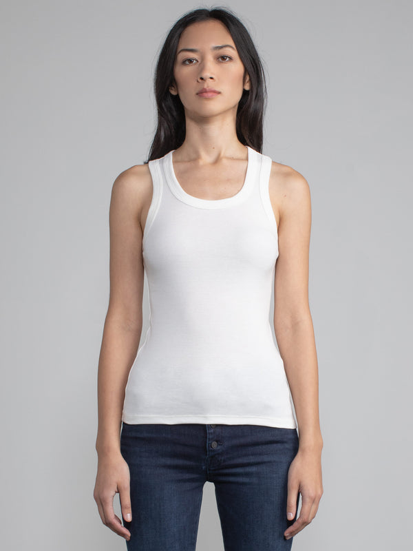 Portrait view of a woman wearing a fitted ribbed white tank.