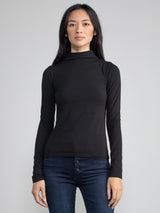 Portrait view of a woman wearing a black fitted long sleeve turtleneck tee.