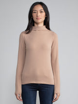 Portrait view of a woman wearing a light brown fitted long sleeve turtleneck tee.