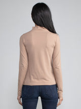 Back view of a woman wearing a light brown fitted long sleeve turtleneck tee.
