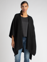 Model wears a white ribbed button up top and a pair of jean with a black cashmere cape.