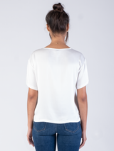 Back view of the model wearing a white silk tee and a pair of jeans.
