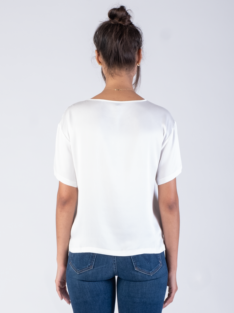 Back view of the model wearing a white silk tee and a pair of jeans.