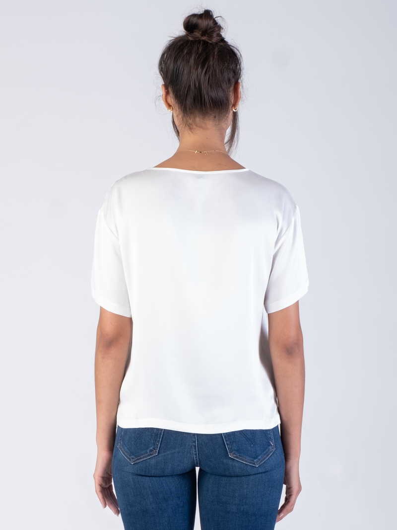 Back view of the model wearing a white silk tee and a pair of jeans.