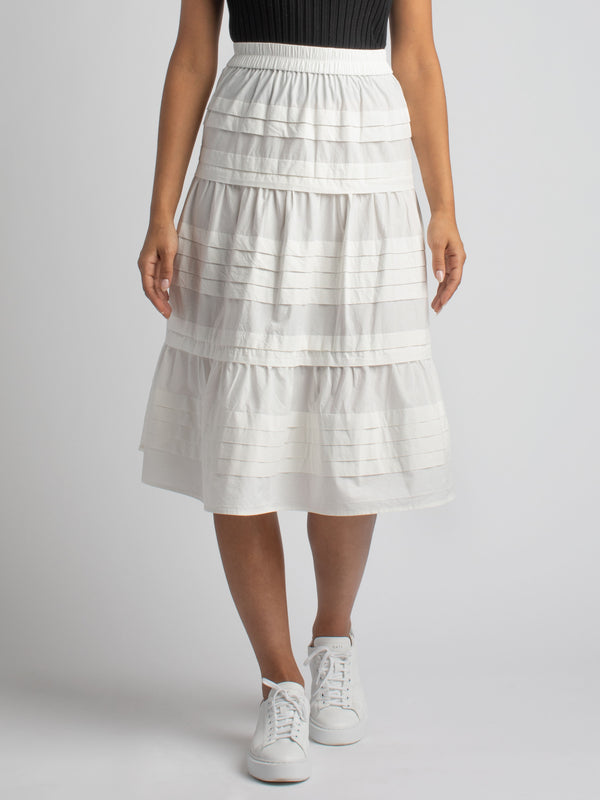 Model wearing a white skirt with horizontal pin tucked details. 