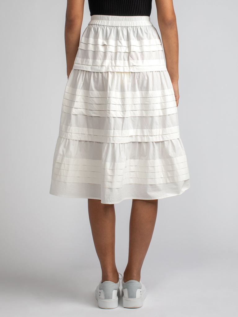 Back view of the model wearing a white skirt with horizontal pin tucked details.