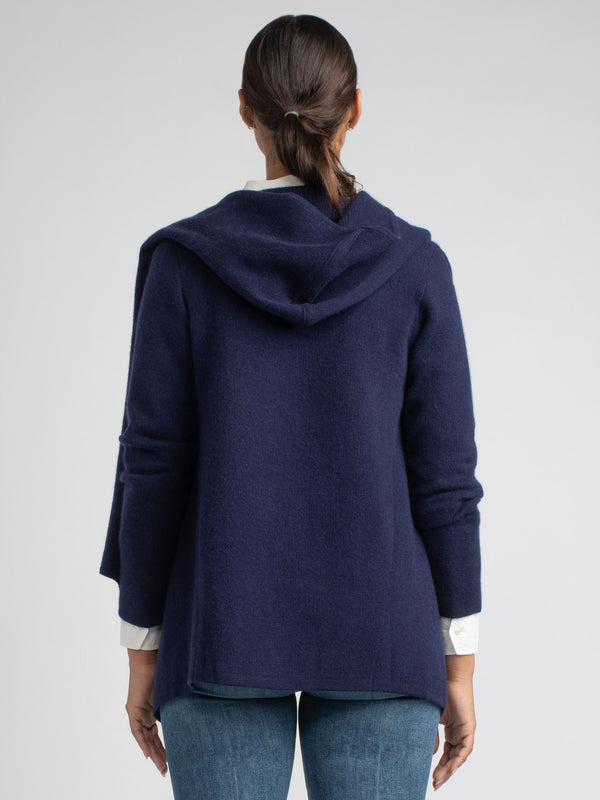 Back view of the model wearing a white shirt underneath a navy cashmere coat and a pair of jeans.