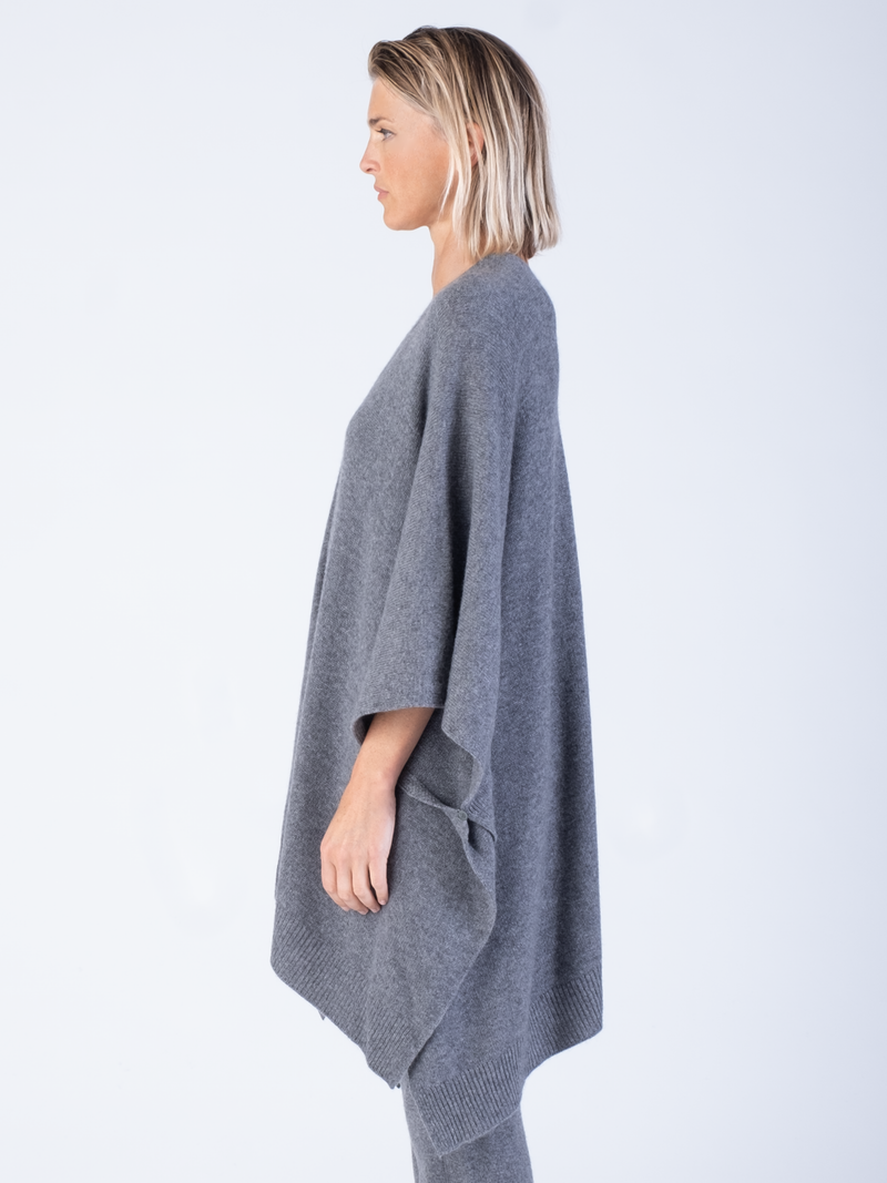 Side view: Model wears a white crew tee and a pair of grey joggers with a grey cashmere cape.