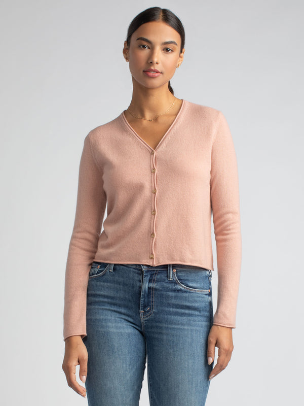 Model wearing a pink lightweight cashmere cardigan and a pair of jeans. 