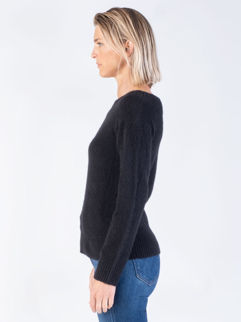 Side view of the model wearing a black pullover and a pair of pants.