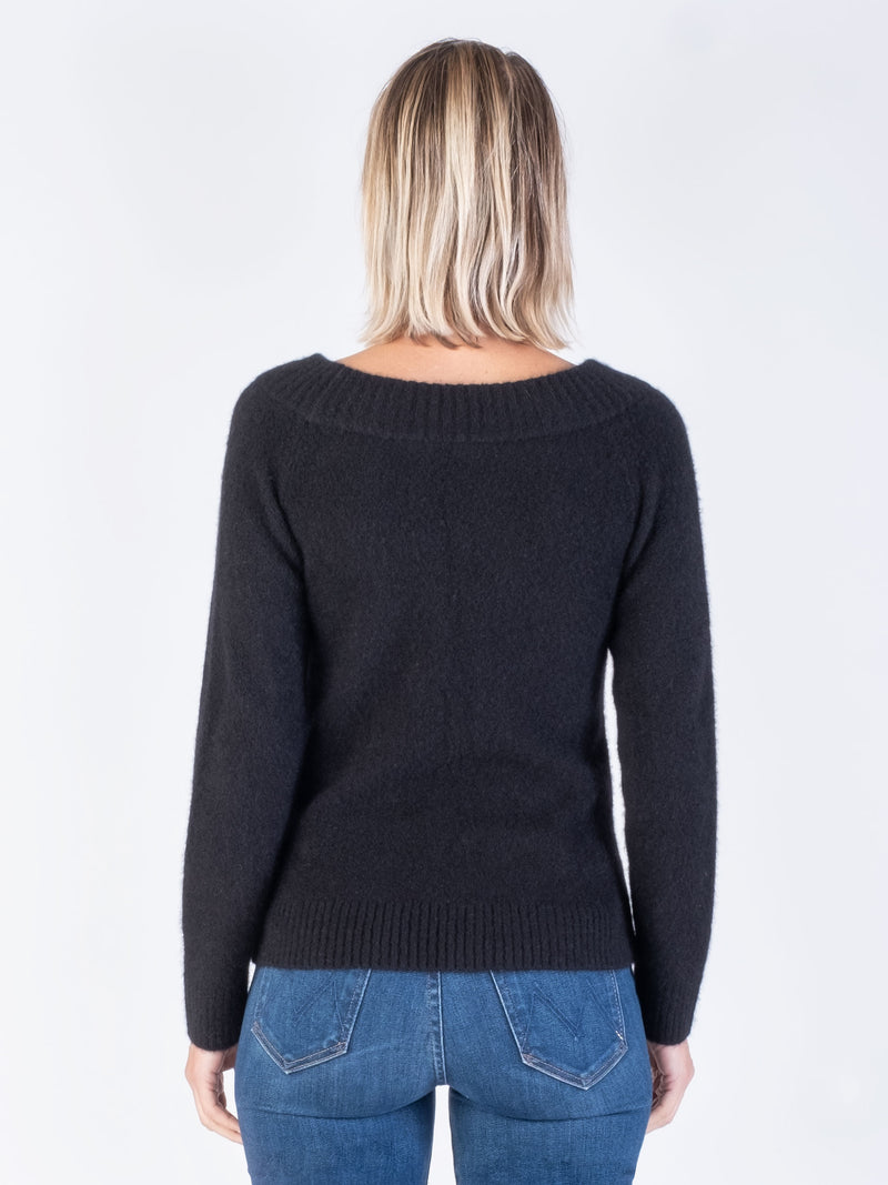 Back view of the model wearing a black pullover and a pair of pants.