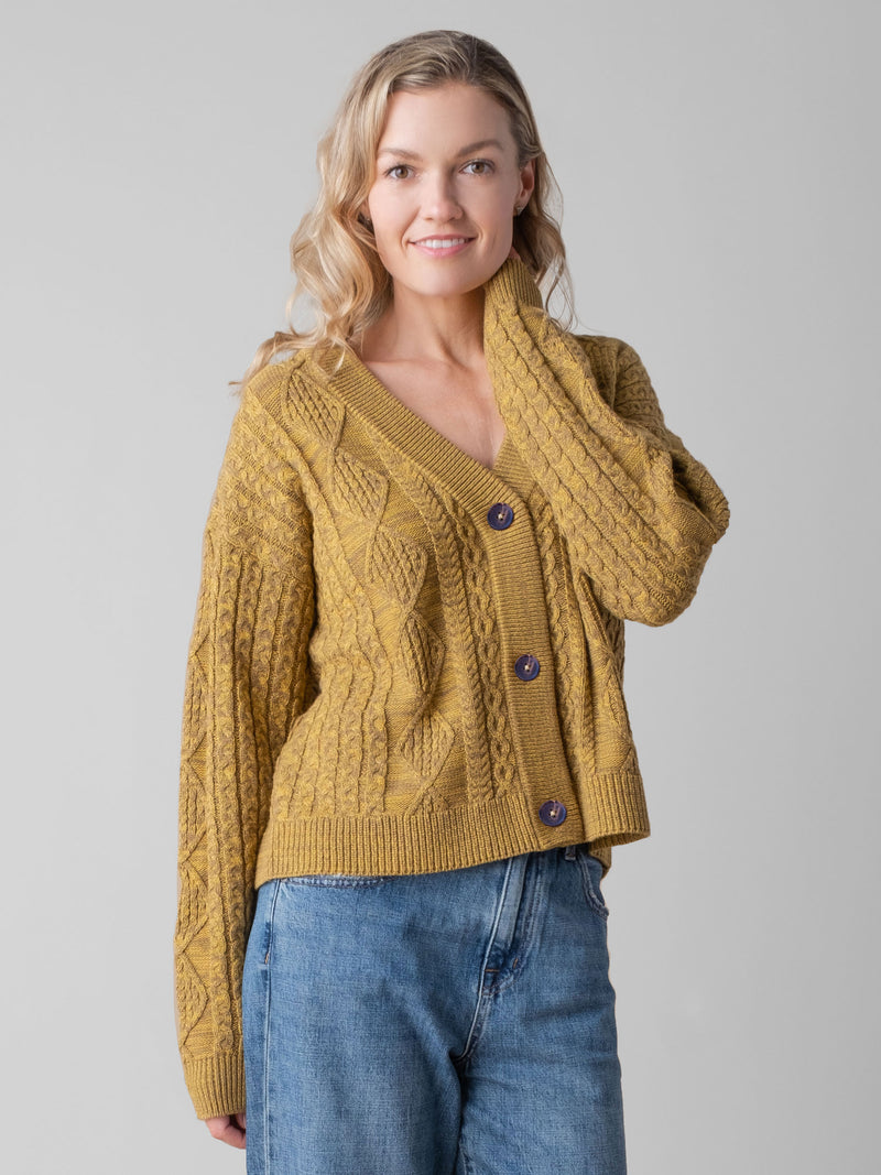Model wearing a yellow cable cardigan and a pair of denim pants.