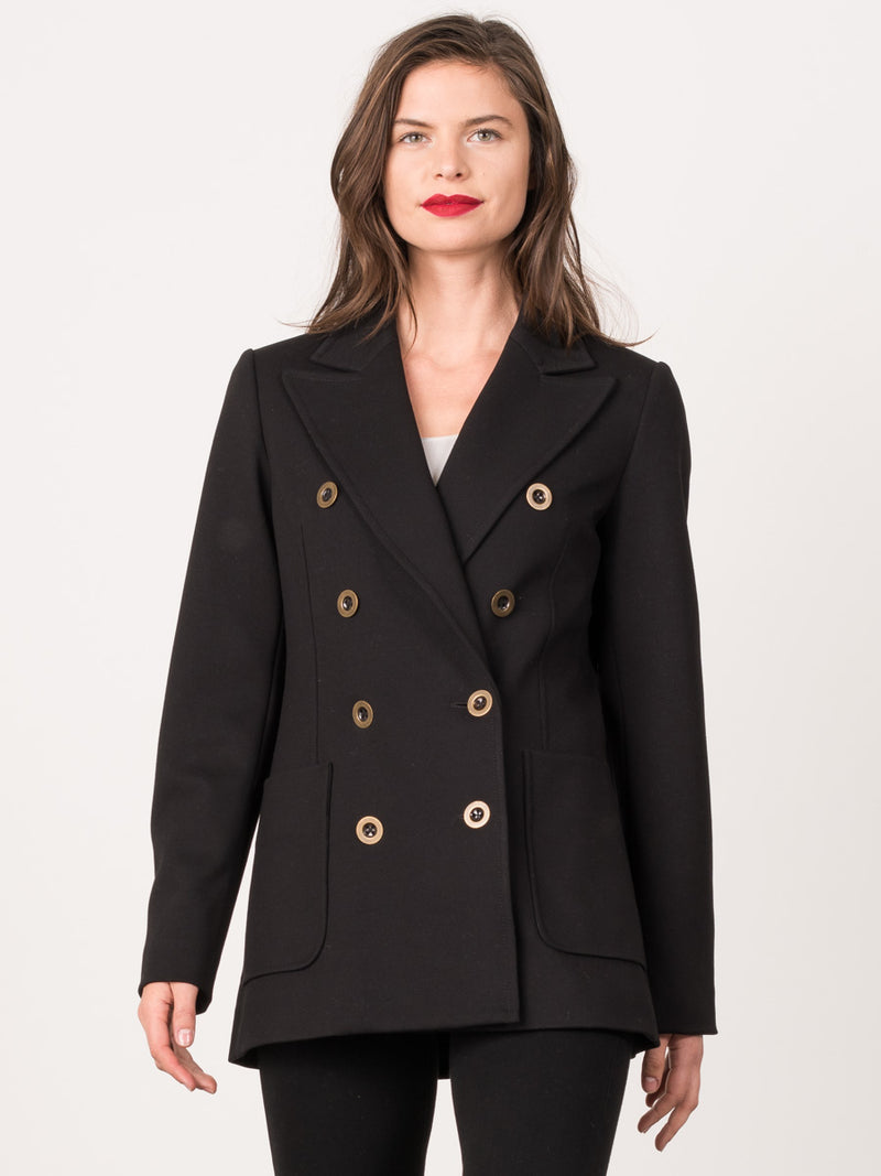 Female model wearing a black peacoat with eight gold circular buttons and two pockets.