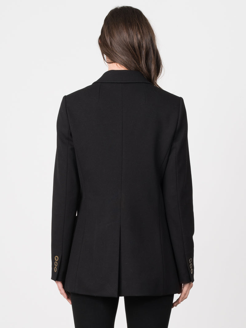 Back view of the model wearing a black peacoat with eight gold circular buttons and two pockets.