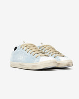 A pair of distressed denim lowtop sneakers, set against a bright white background.