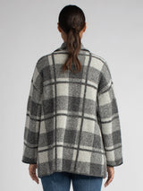Back view of the model wearing a black and grey plaid jacket and a white rib top underneath and a pair of jeans.