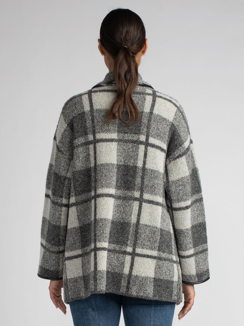 Back view of the model wearing a black and grey plaid jacket and a white rib top underneath and a pair of jeans.