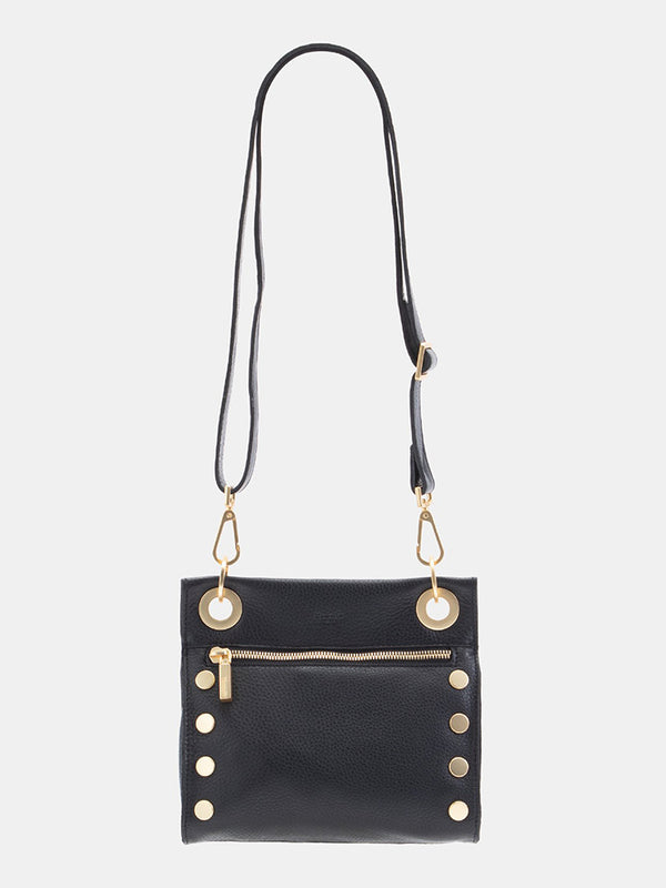 A black crossover bag with circular gold hardware at sides and by the strap and a gold zipper under the circular hardware by the strap. 