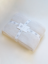 Folded off-white blanket wrapped in a Margaret O'Leary branded ribbon.