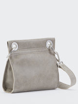 Back view of a grey crossover bag with circular silver hardware by the strap and a phone pocket between the circular silver hardware.