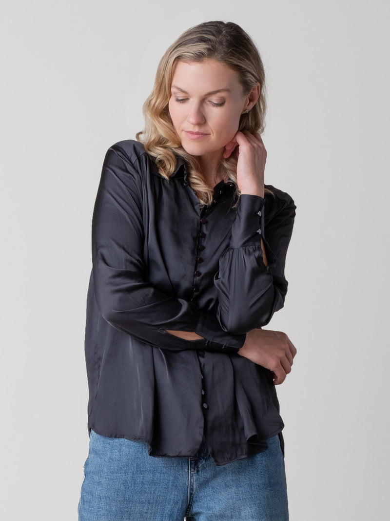 Model wearing a black blouse with a button closure and a pair of jeans.