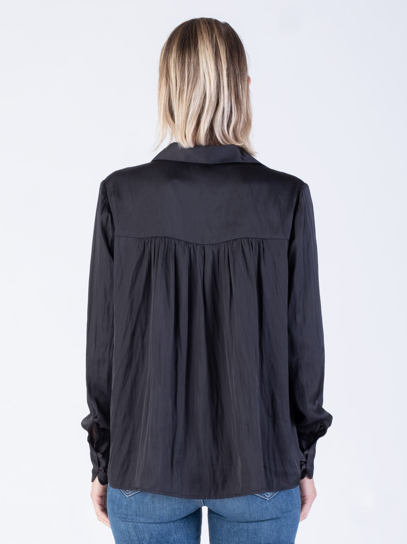 Back view of the model wearing a black blouse with a button closure and a pair of jeans.