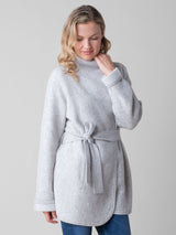 Model wearing a light grey two pockets jacket with a waist tie and a pair of jeans.