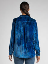 Back view of the model wearing a blue velvet shirt and a pair of jeans.
