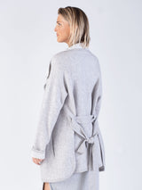 Back view of the model wearing a light grey two pockets jacket with a waist tie