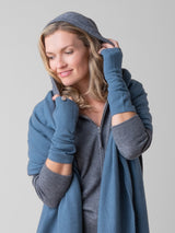 Model wearing a grey hoodie and a pair of grey blue texting gloves and a same blue wrap around her shoulders.