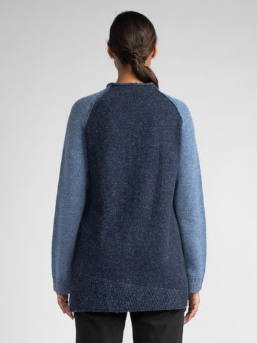 Back view of the model wearing a navy pullover with contrast-color raglan sleeves.