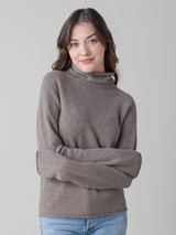 Model wearing a grain color turtleneck pullover and a pair of jeans.