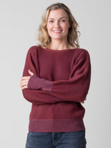 Front view of the model wearing a ribbed red pullover and a pair of jeans.