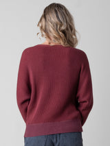 Back view of the model wearing a ribbed red pullover and a pair of jeans.